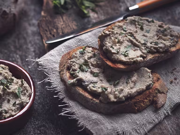 A pate made of mushrooms and Quorn Pieces spread on two pieces of rustic white bread.