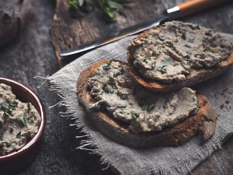 A pate made of mushrooms and Quorn Pieces spread on two pieces of rustic white bread.