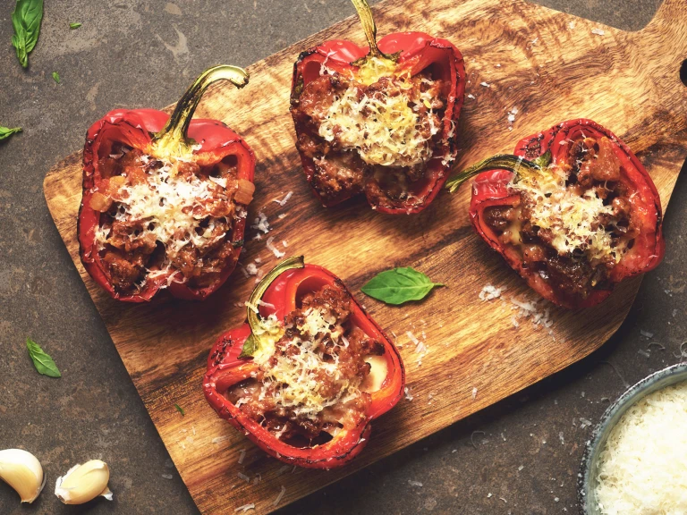 Four Quorn vegetarian stuffed peppers served on a wooden board.