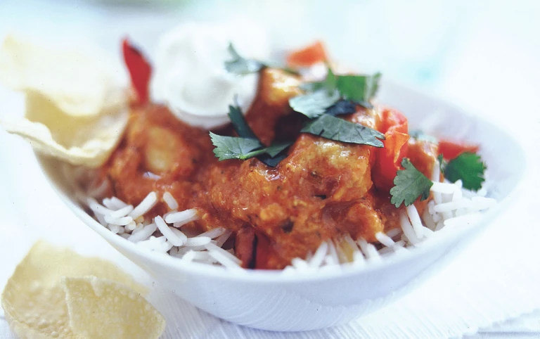 Quorn Pieces tikka masala on a bed of rice topped with yoghurt and coriander.