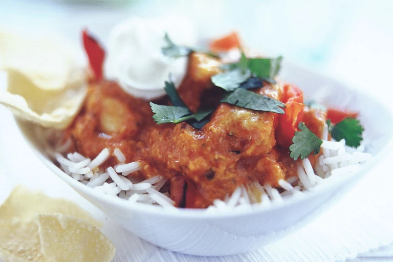 Quorn Pieces tikka masala on a bed of rice topped with yoghurt and coriander.