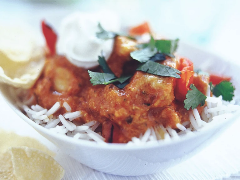 Quorn Pieces tikka masala on a bed of rice topped with yoghurt and coriander.