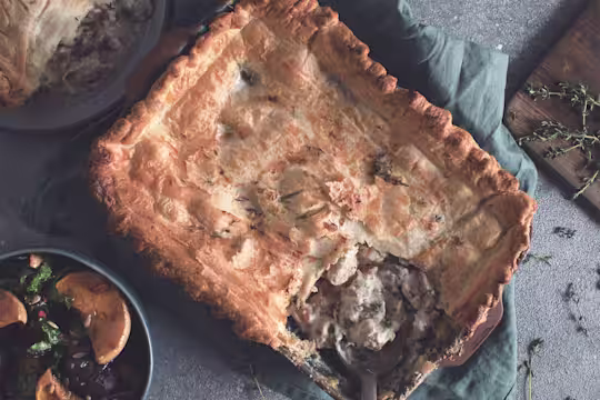 A pot pie in the baking dish with a portion removed to reveal a filling of Quorn Fillets, brie, fennel, and mushrooms.