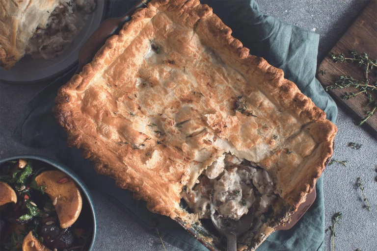 A pot pie in the baking dish with a portion removed to reveal a filling of Quorn Fillets, brie, fennel, and mushrooms.