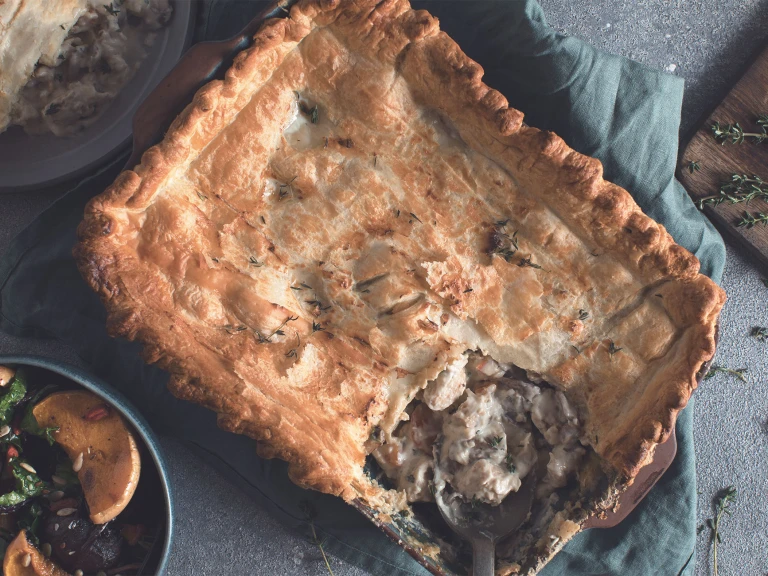 A pot pie in the baking dish with a portion removed to reveal a filling of Quorn Fillets, brie, fennel, and mushrooms.