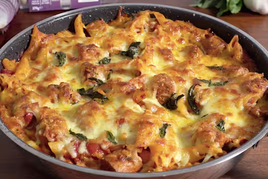 Tomato Vegan sausage pasta topped with cheese and served in an oven dish