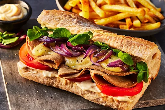 A Quorn vegetarian roast beef steak sandwich featuring Quorn Roast Beef Slices served with a side of chips.