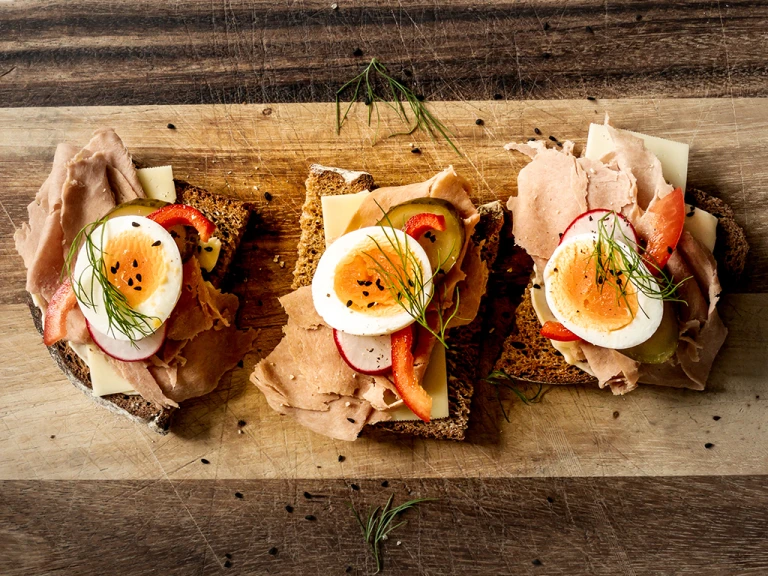 Danish Style Smørrebrød Open Sandwich with Finely Sliced Ham Style Slices on a wooden board
