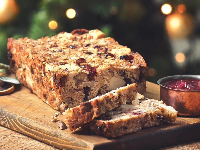 Meatless nut loaf made with Quorn pieces, chestnuts and cranberries next to a pot of sauce