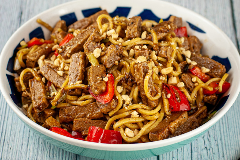 Vegetarian black bean stir fry with Quorn steak strips served in a bowl with chopsticks on the side.
