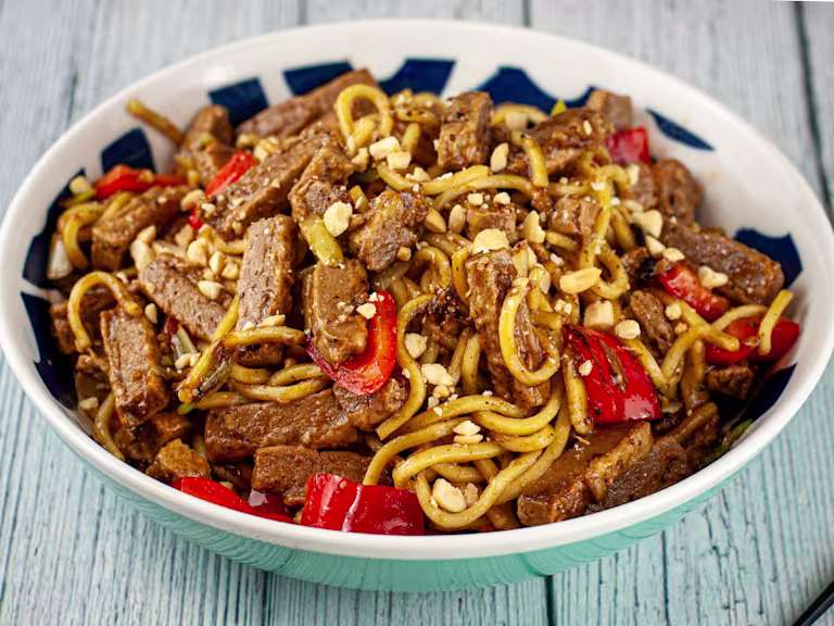 Vegetarian black bean stir fry with Quorn steak strips served in a bowl with chopsticks on the side.