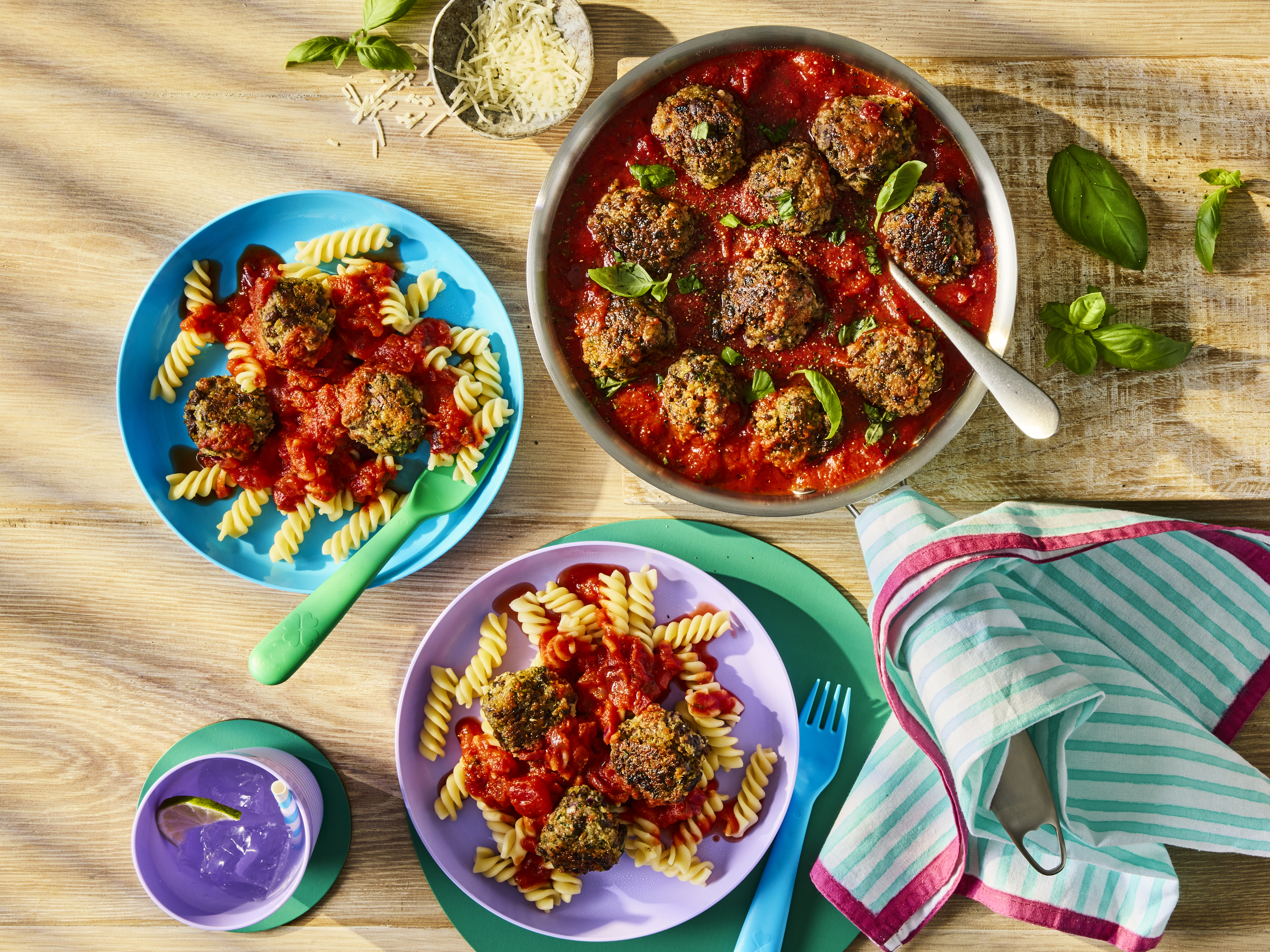 Meatballs in a rich tomato sauce served with fusilli pasta and fresh basil leaves.