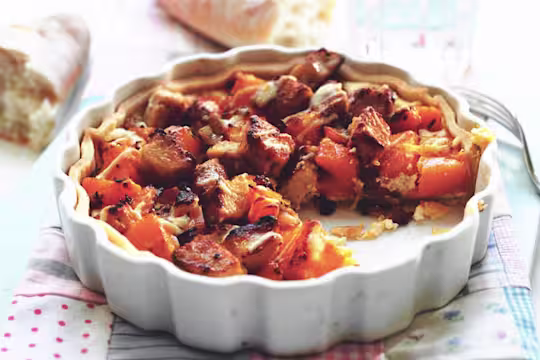 Quick and easy meal of butternut squash tart made with Quorn Pieces served in a fluted ceramic dish with a portion cut out