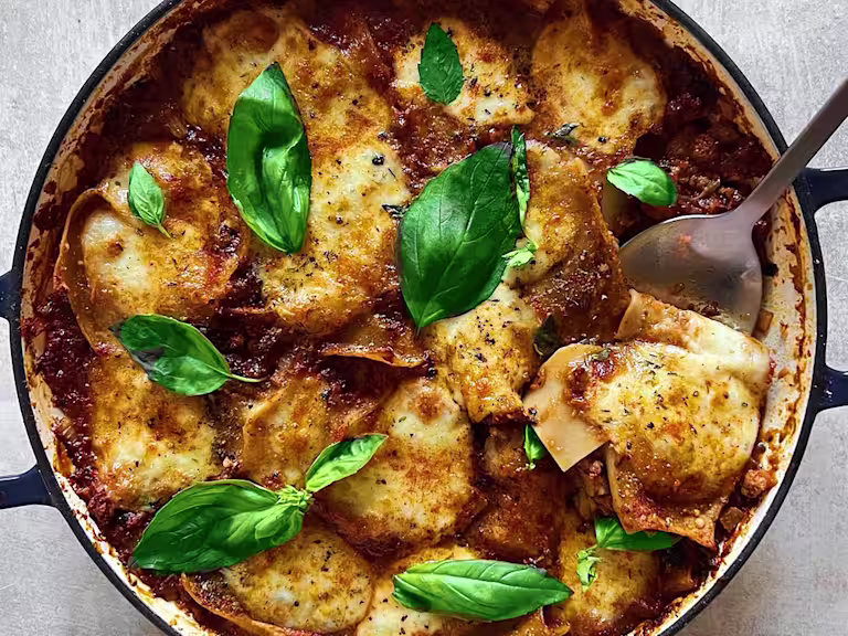 A large pot of vegetarian lasagne made using Quorn Mince topped with basil leaves.