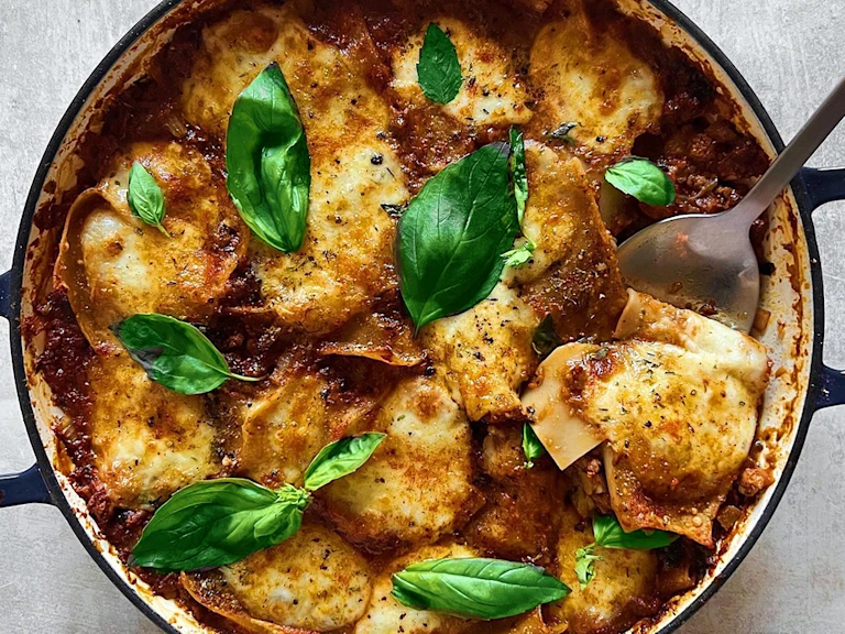 A large pot of vegetarian lasagne made using Quorn Mince topped with basil leaves.