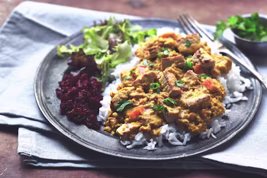 A plate of vegetarian katsu curry with Quorn Pieces, rice and a side salad.