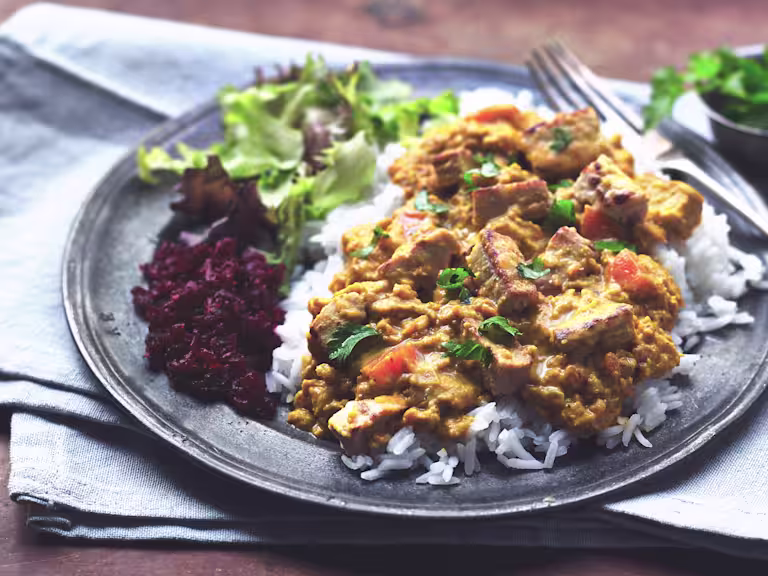 A plate of vegetarian katsu curry with Quorn Pieces, rice and a side salad.