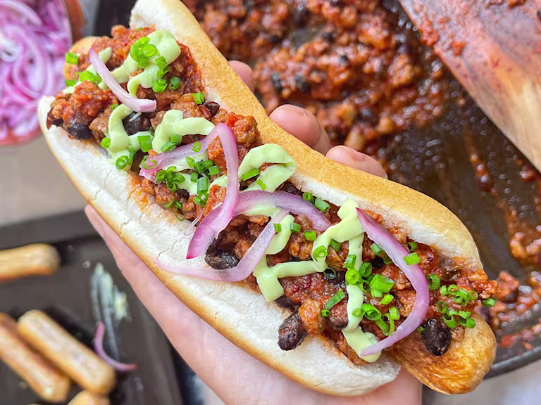 Quorn chilli dog with chilli in the background.