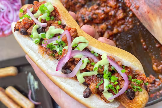 Quorn chilli dog with chilli in the background.