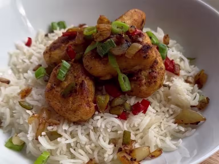 Quorn Crispy Nugget sat on top of a red of rice topped with garnish.