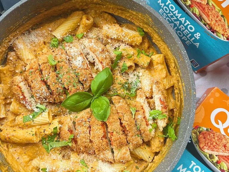 A bowl of pumpkin pasta topped with two sliced Quorn Tomato and Mozzarella Escalopes.