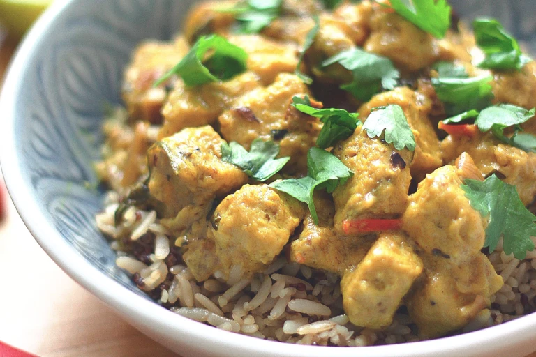 Meat-free curry made Quorn pieces in a lime and coconut sauce served on a bowl of rice garnished with chopped coriander