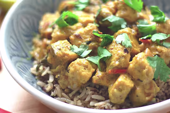 Meat-free curry made Quorn pieces in a lime and coconut sauce served on a bowl of rice garnished with chopped coriander