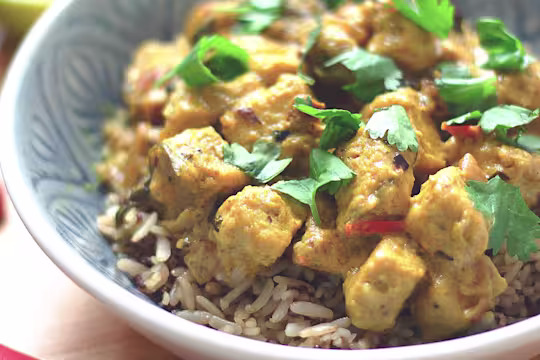 Vegan curry made Quorn vegan pieces in a lime and coconut sauce served on a bowl of rice garnished with chopped coriander