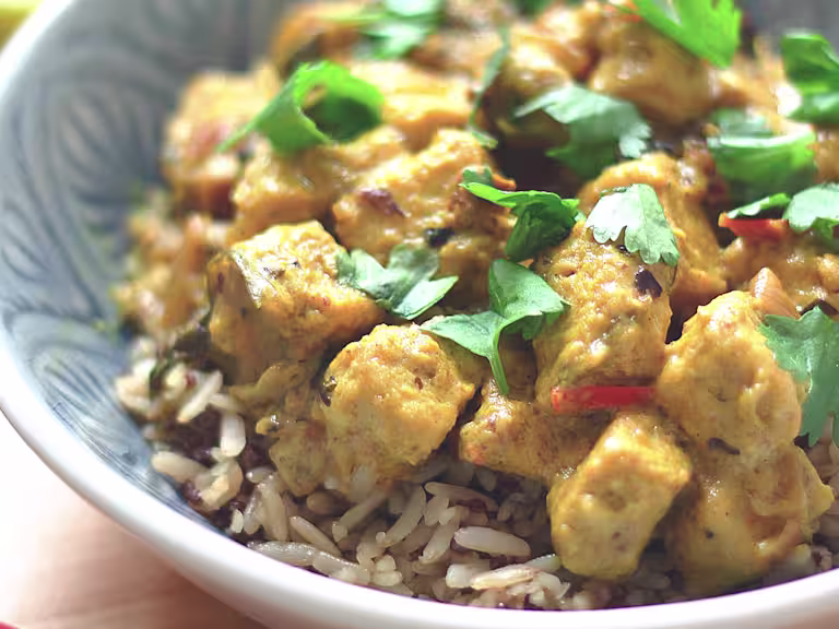 Vegan curry made Quorn vegan pieces in a lime and coconut sauce served on a bowl of rice garnished with chopped coriander