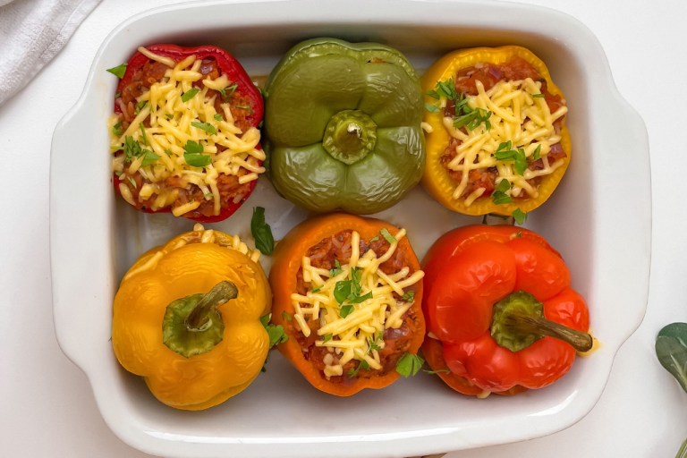 Six stuffed peppers served in a white dish.