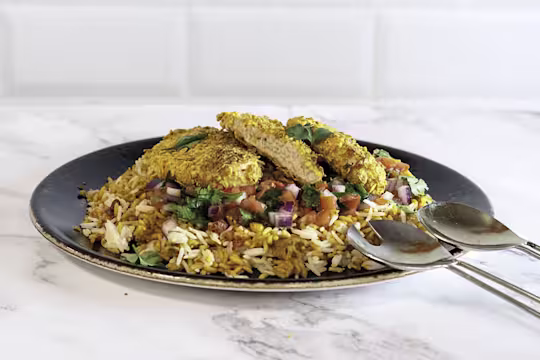 Dorito-crumbed Quorn Fillets atop a bed of rice with a tomato, red onion, and coriander salsa.