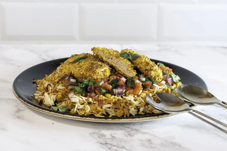 Dorito-crumbed Quorn Fillets atop a bed of rice with a tomato, red onion, and coriander salsa.