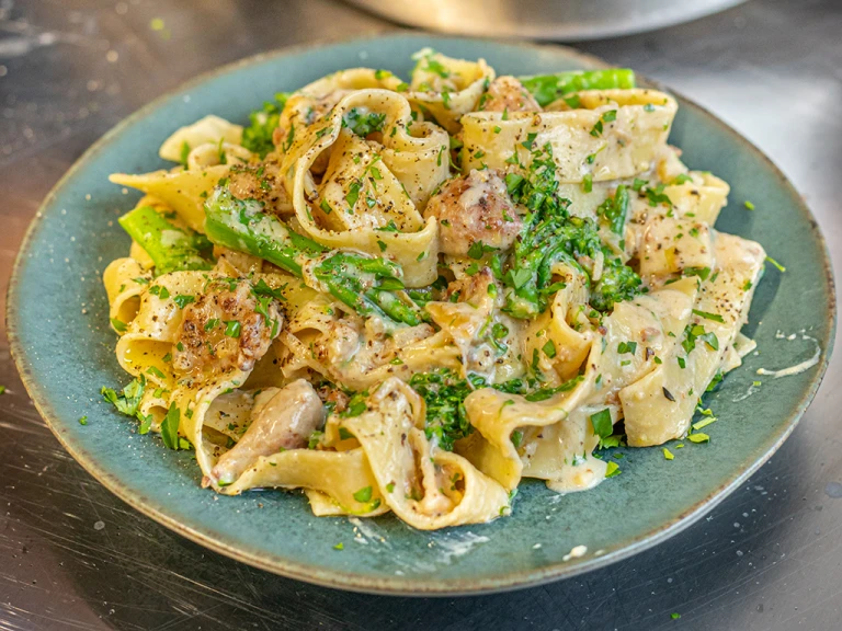 Creamy sausage and broccoli pasta served on a green plate