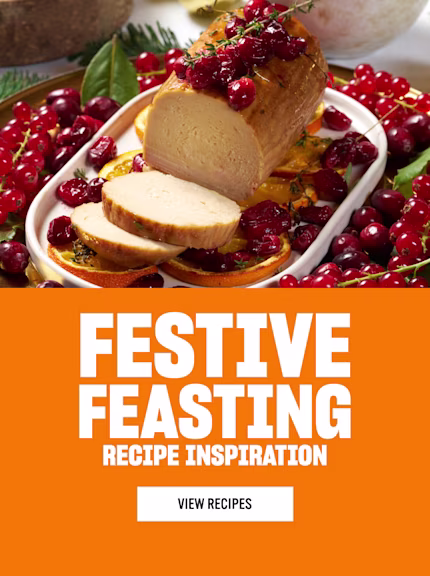 A festive dish featuring a sliced roast topped with cranberries and herbs, surrounded by red currants, cranberries, and side dishes in the background and ‘Festive Feasting’ text on the right.