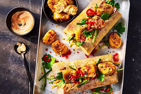 Two Quorn vegetarian Banh Mi served on a tray with sauce on the side
