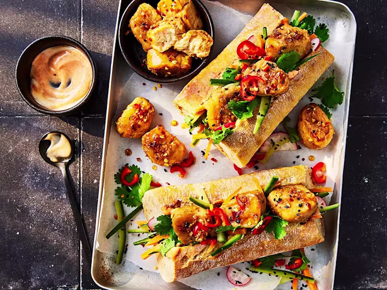 Two Quorn vegetarian Banh Mi served on a tray with sauce on the side