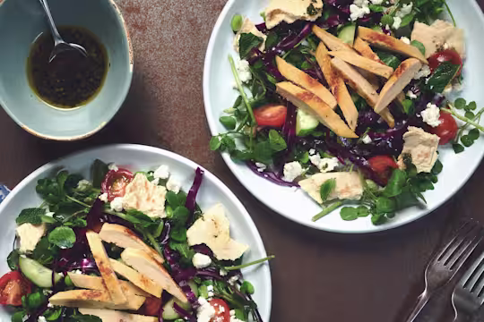 A salad of red cabbage, broad beans, tomatoes, cucumber, watercress, and feta topped with Quorn Roast Mini Fillets.