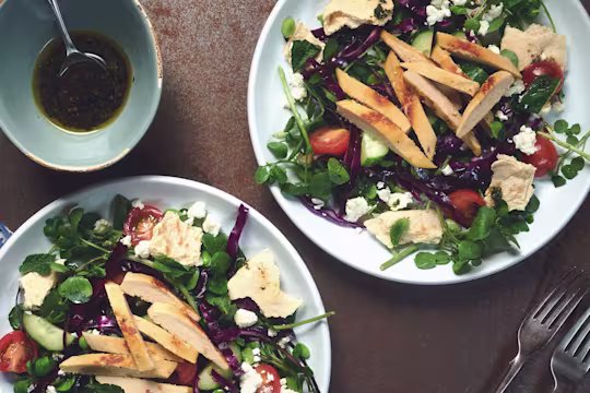 A salad of red cabbage, broad beans, tomatoes, cucumber, watercress, and feta topped with Quorn Roast Mini Fillets.