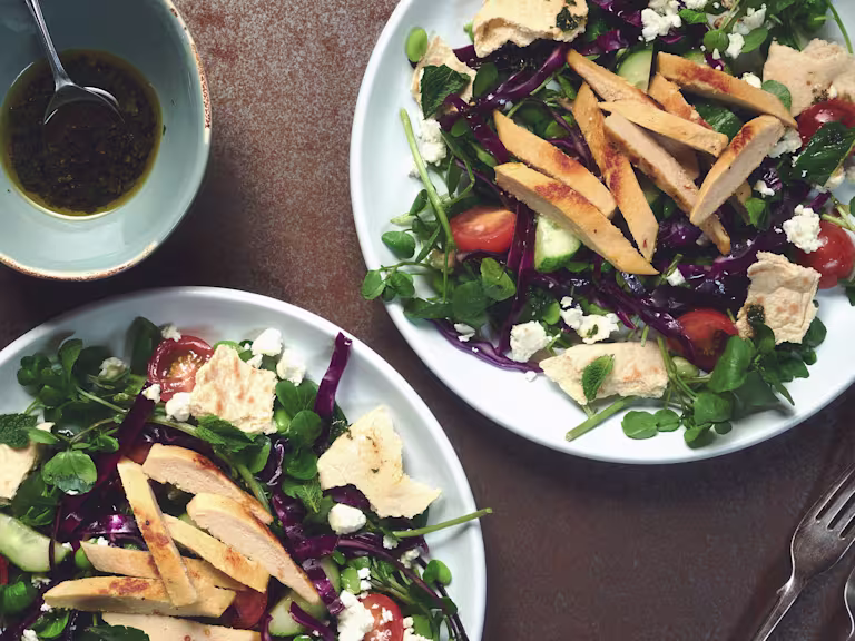 A salad of red cabbage, broad beans, tomatoes, cucumber, watercress, and feta topped with Quorn Roast Mini Fillets.