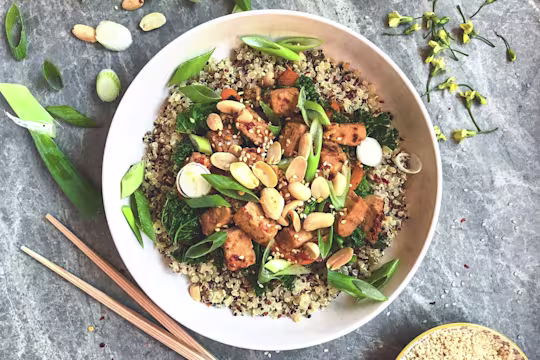 An Asian dish made with Quorn Vegan Pieces and an orange sauce topped with peanuts and sesame seeds atop a bed of quinoa.