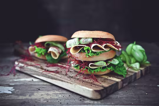 Healthy lunch idea of bagels filled with Quorn Vegan Chicken Free Slices, layered with salad served on a wooden board