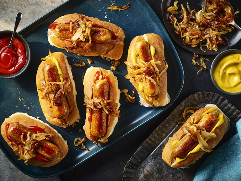 A hot dog platter made with Quorn Sausages, mustard, and gherkins in a shallow Dutch oven.