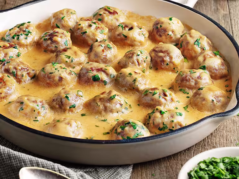 Creamy Swedish meatballs presented in a white oven dish
