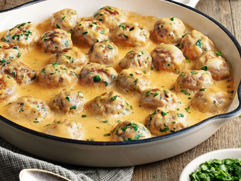 Creamy Swedish meatballs presented in a white oven dish 