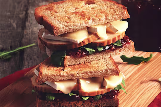Two wholegrain bread sandwiches filled with Quorn Roast, cranberry sauce, brie, and rocket.