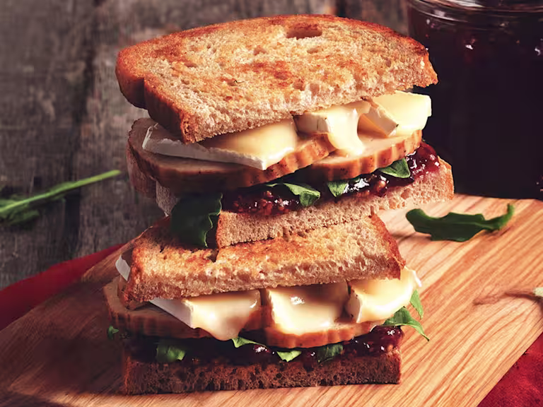Two wholegrain bread sandwiches filled with Quorn Roast, cranberry sauce, brie, and rocket.