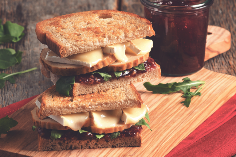 Two wholegrain bread sandwiches filled with Quorn Roast, cranberry sauce, brie, and rocket.