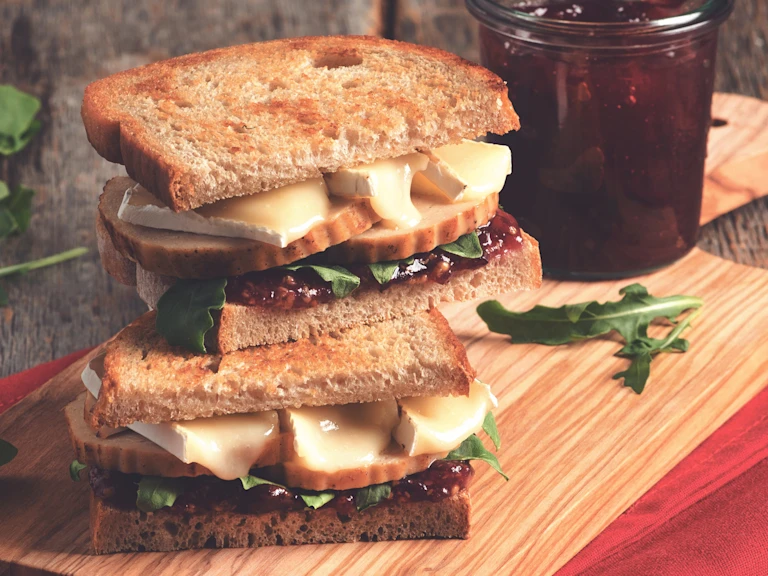 Two wholegrain bread sandwiches filled with Quorn Roast, cranberry sauce, brie, and rocket.