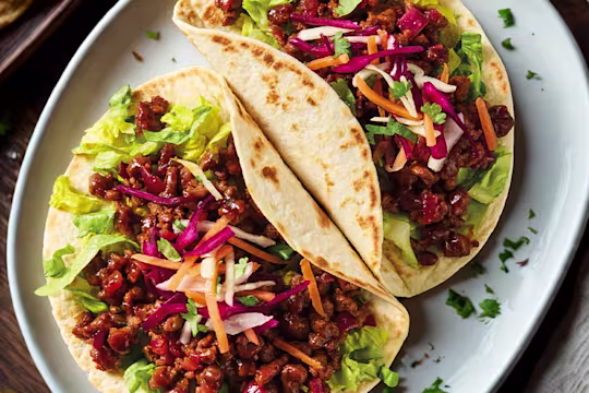 Korean BBQ Quorn mince tacos with salad on a white plate.