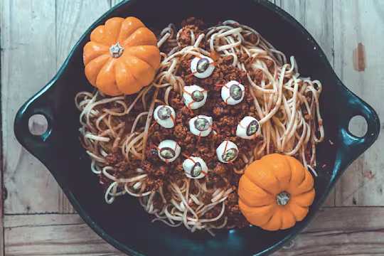A bowl of spaghetti with Quorn Grounds Bolognese sauce topped with mozzarella 'eyes' and two mini pumpkins as décor.